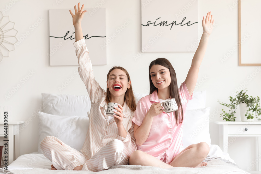 Female friends drinking coffee in bedroom