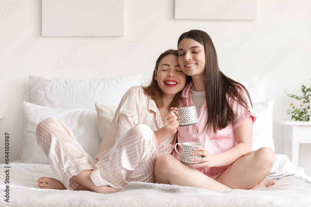 Female friends drinking coffee in bedroom