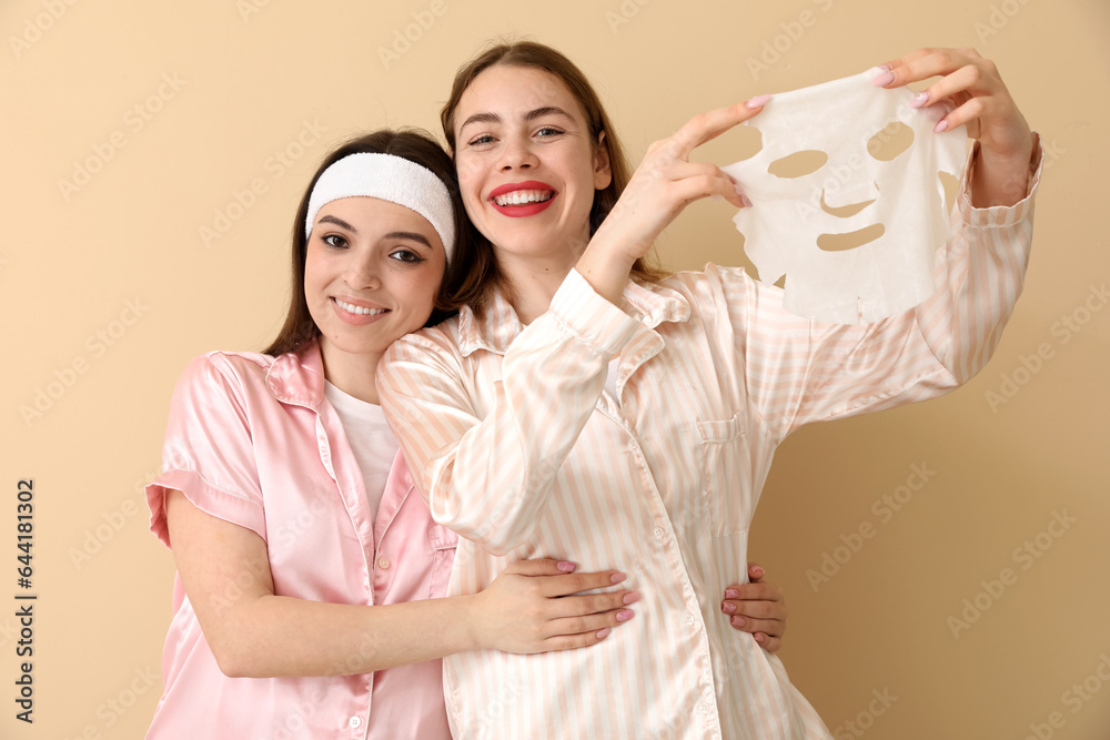 Female friends with facial mask on beige background