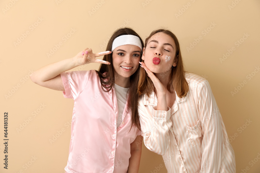 Female friends in pajamas with cream on beige background