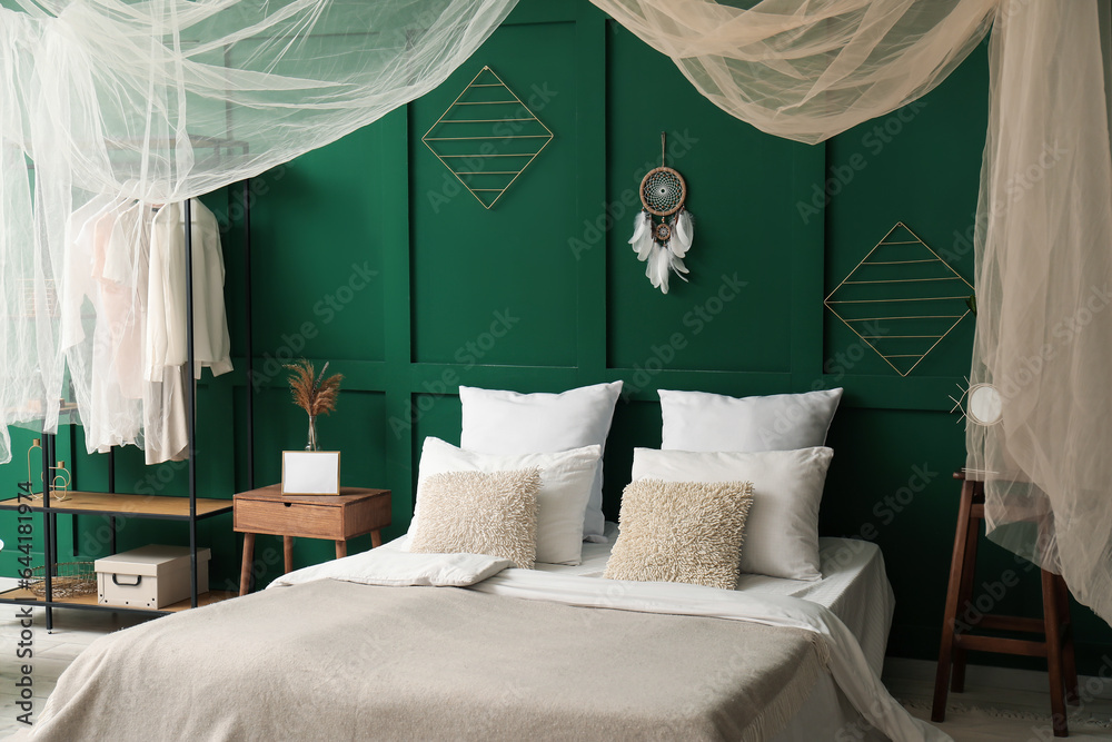 Interior of stylish bedroom with curtain and dream catcher on green wall