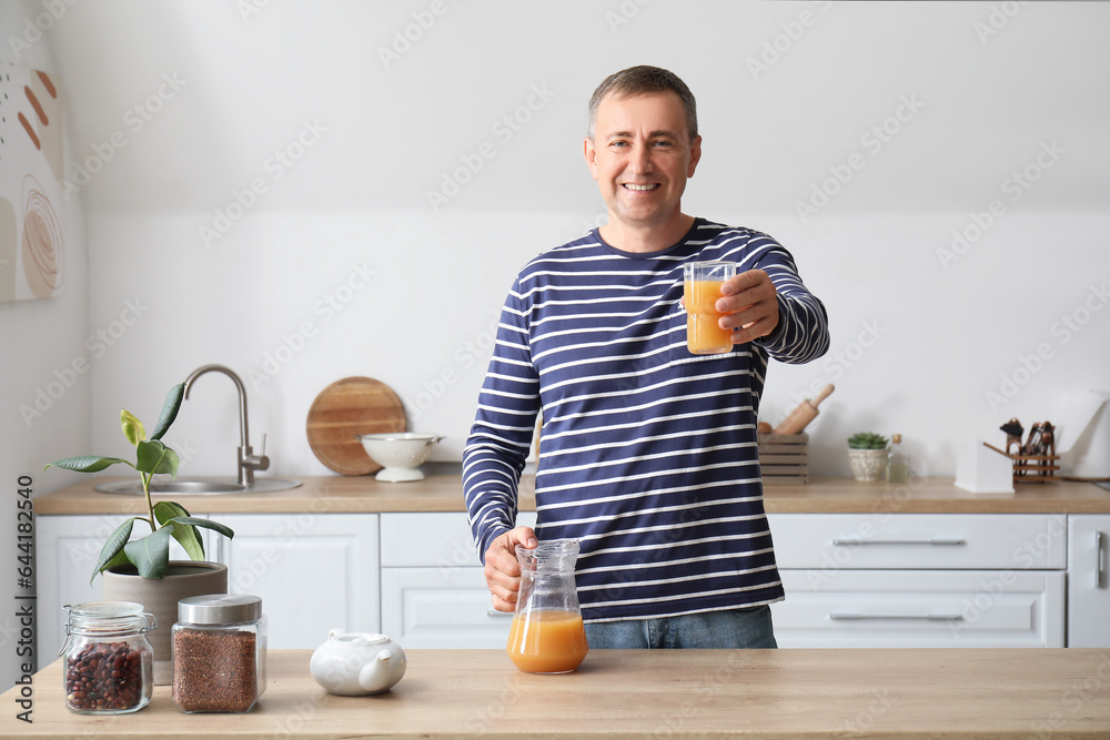 Mature man with glass of orange juice in kitchen