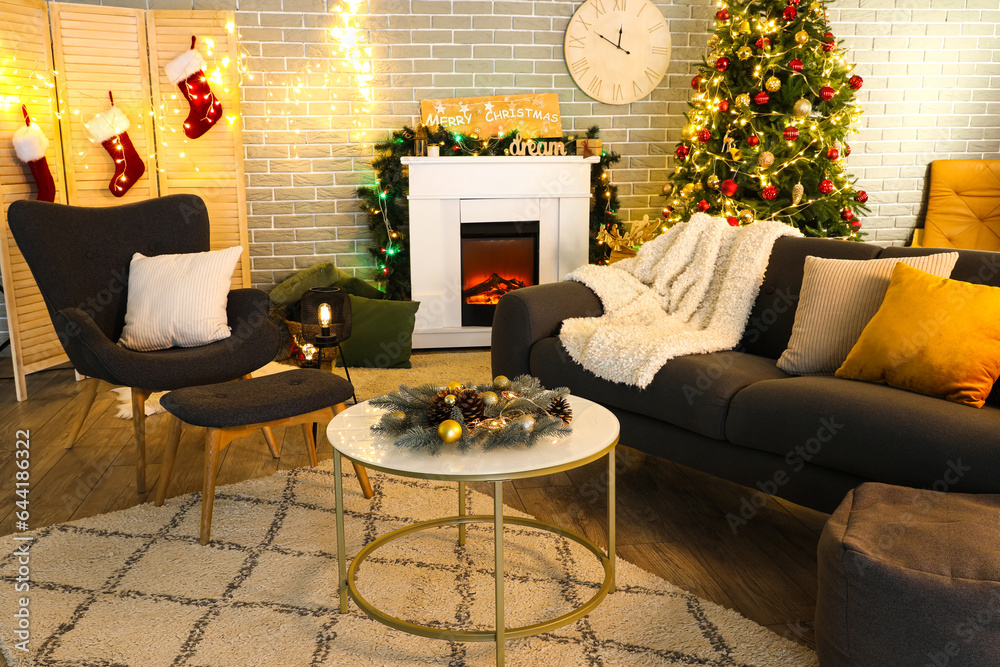 Interior of dark living room with sofa, armchair, fireplace, Christmas tree and glowing lights