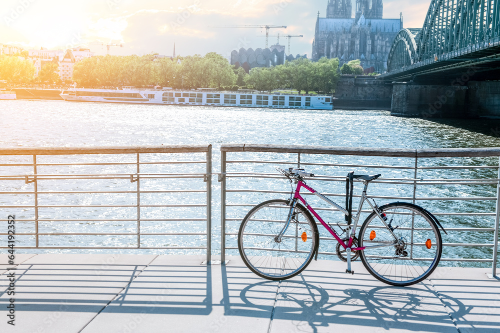 Modern bicycle parked on embankment near river in city