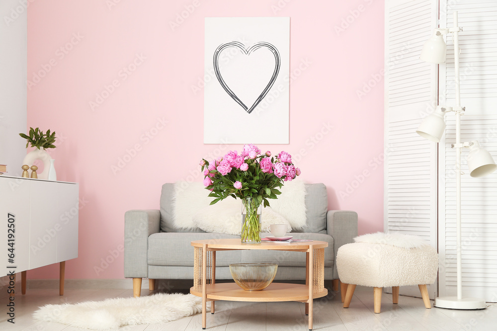 Vase of pink peonies on coffee table with couch in living room