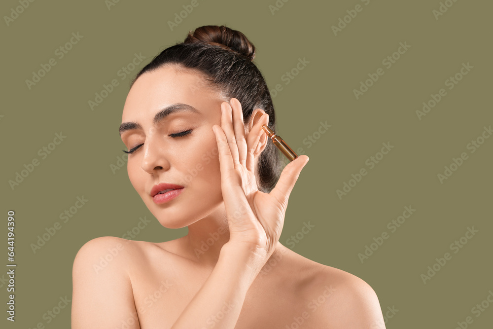 Beautiful young woman with ampule on green background, closeup