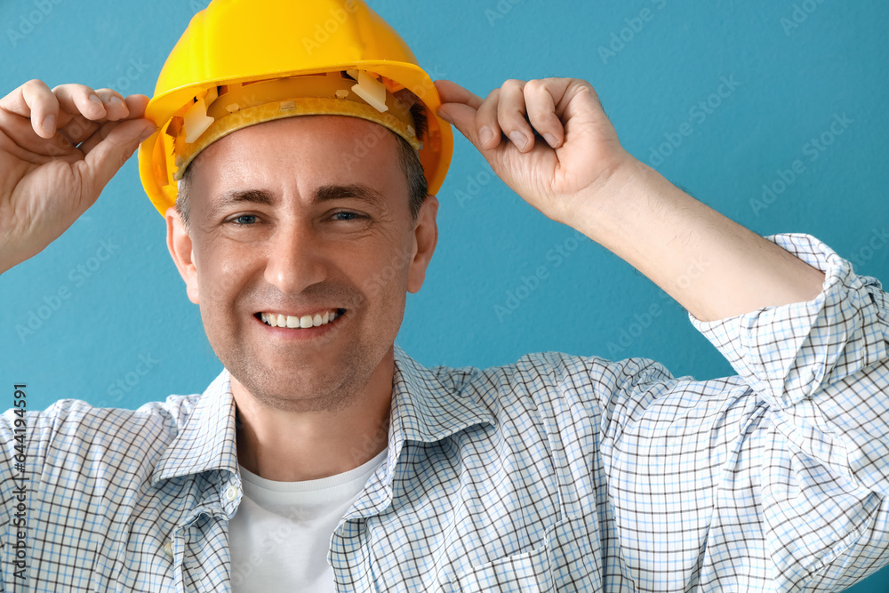 Mature builder in hardhat on blue background, closeup