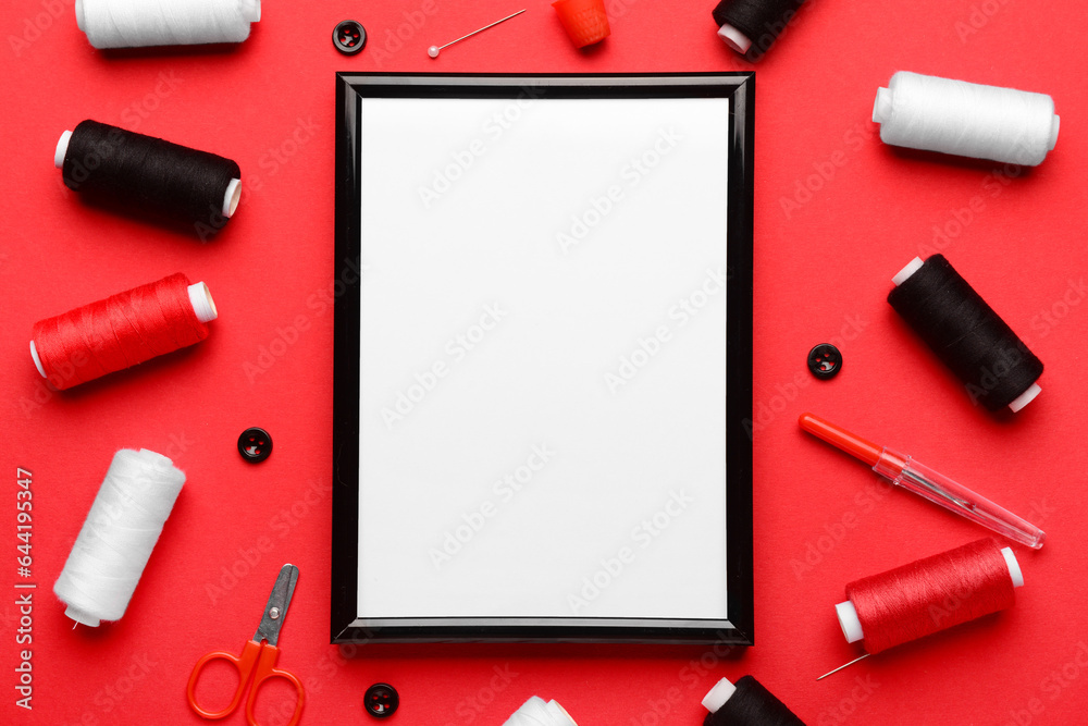 Blank picture frame with sewing supplies on red background