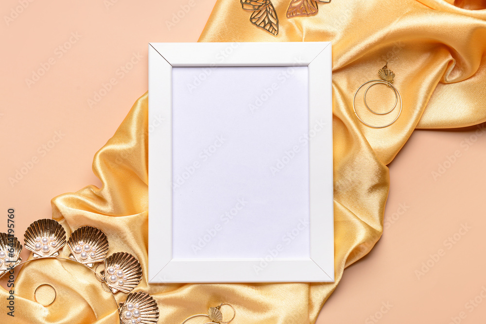 Blank picture frame with accessories and fabric on beige background