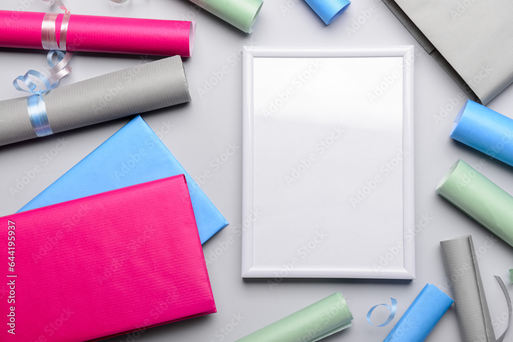 Blank frame with books and wrapping paper on light background