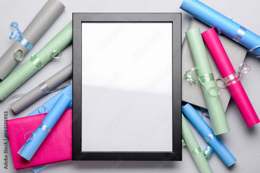 Blank frame with books and wrapping paper on light background