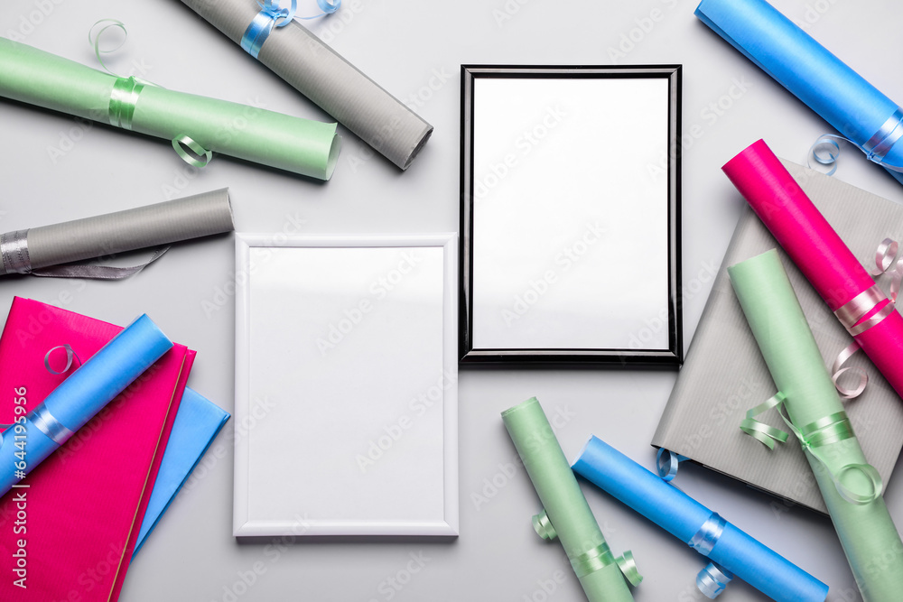 Blank frames with books and wrapping paper on light background