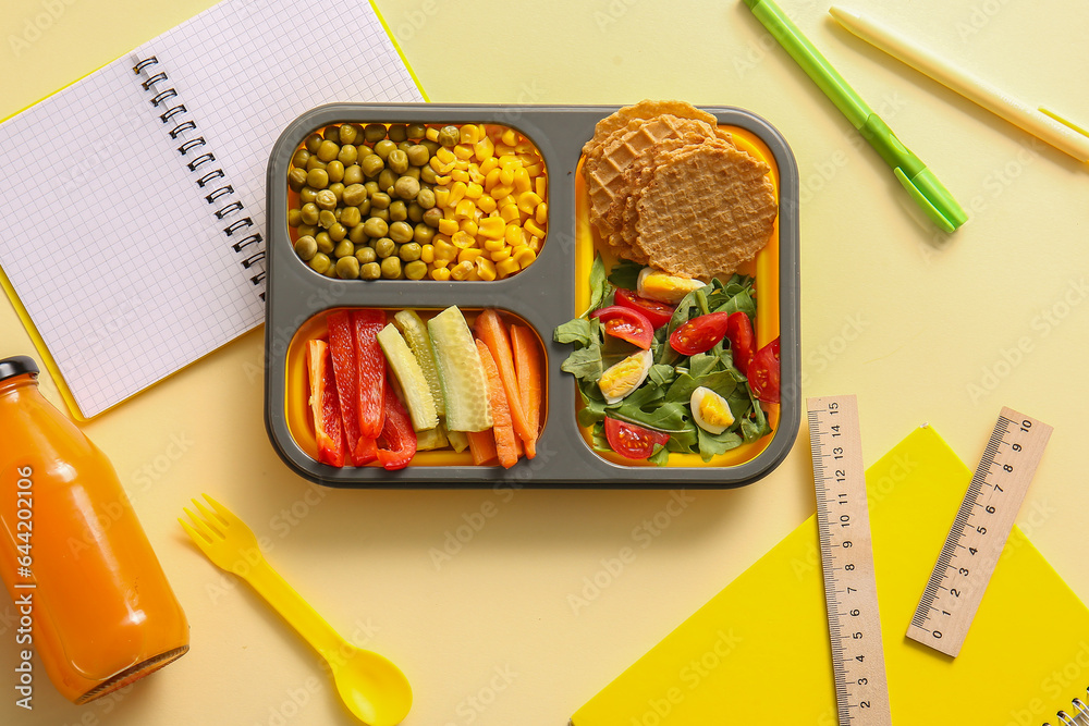 Lunchbox with delicious food and different stationery on pale yellow background