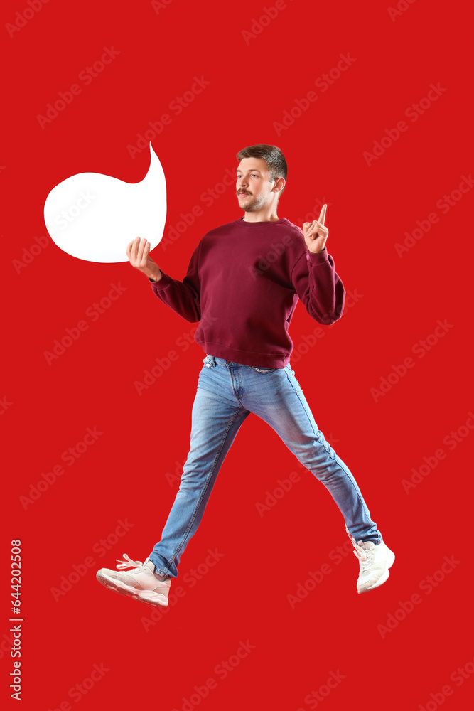 Jumping young man with blank speech bubble on red background