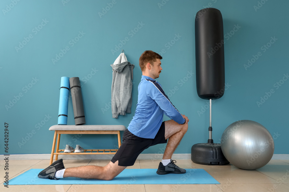 Sporty young man stretching in gym