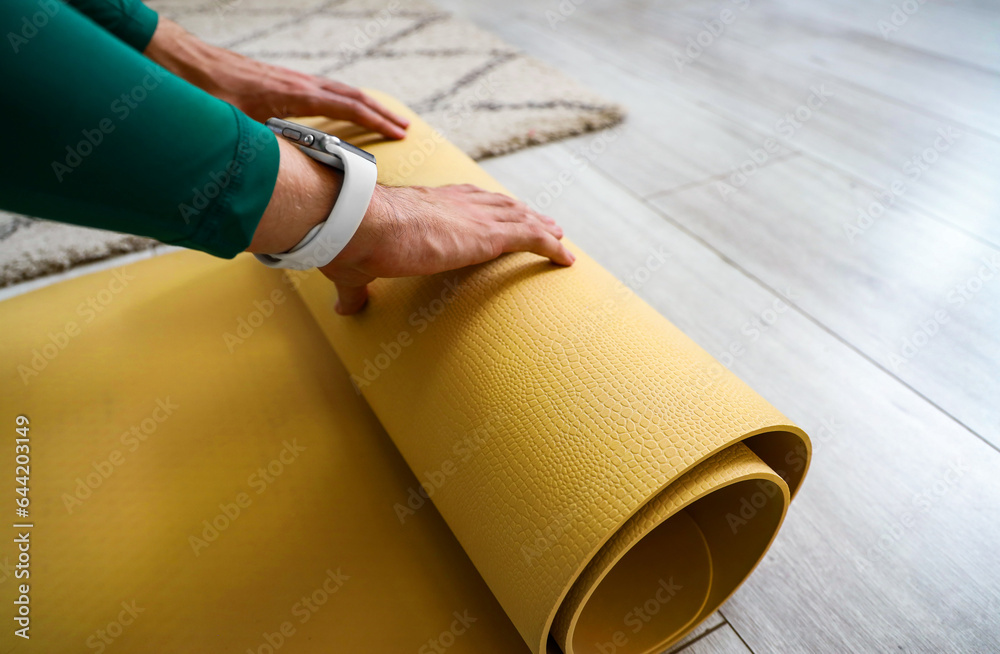 Sporty young man with yoga mat at home, closeup