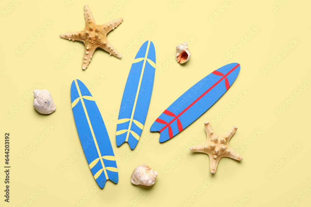 Mini surfboards, starfishes and seashells on yellow background