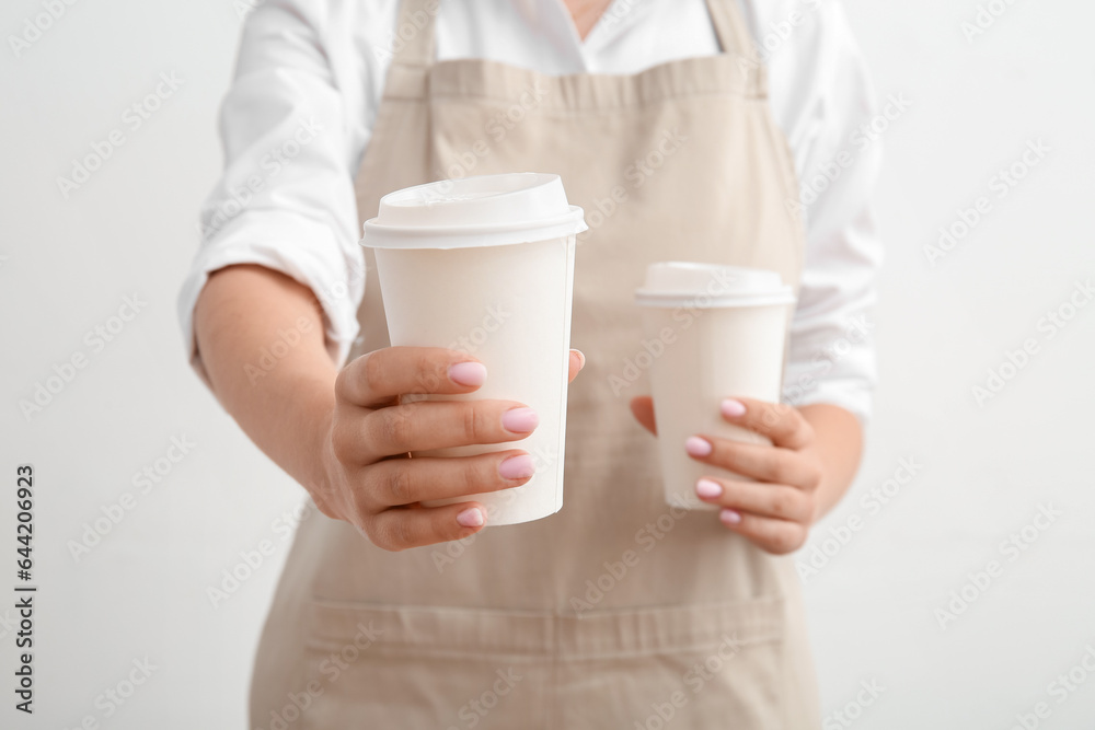 Woman with takeaway cups of hot coffee on white background