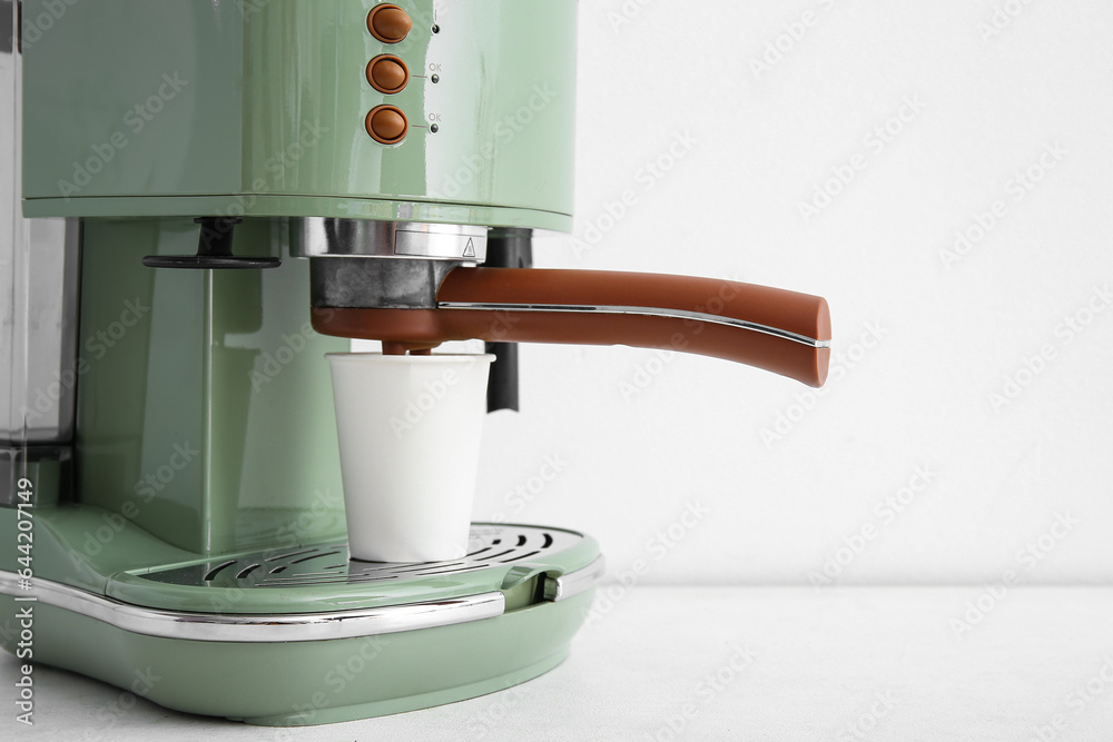 Modern coffee machine with takeaway cup on white background