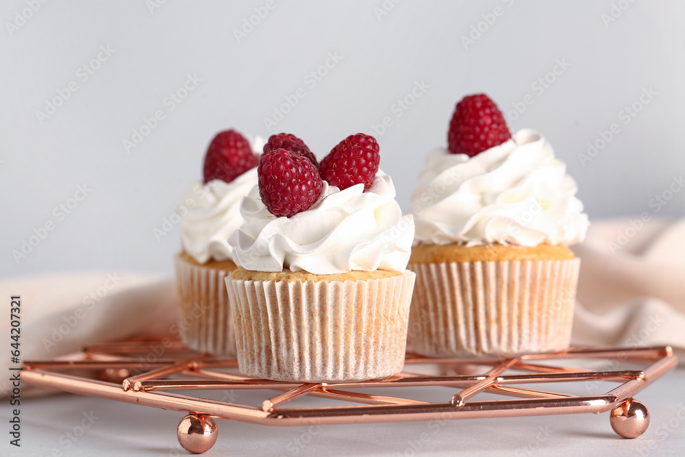 grid with tasty raspberry cupcakes on grey background