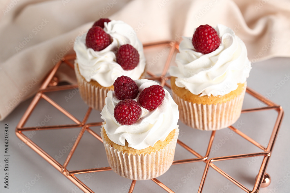 grid with tasty raspberry cupcakes on grey background