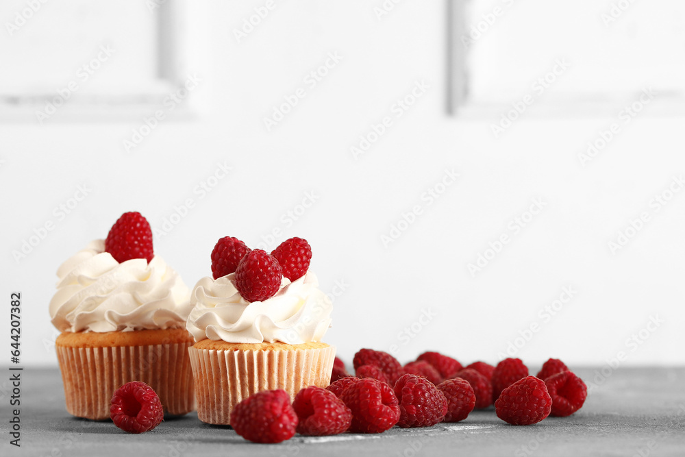 Tasty raspberry cupcakes and fresh berries on table