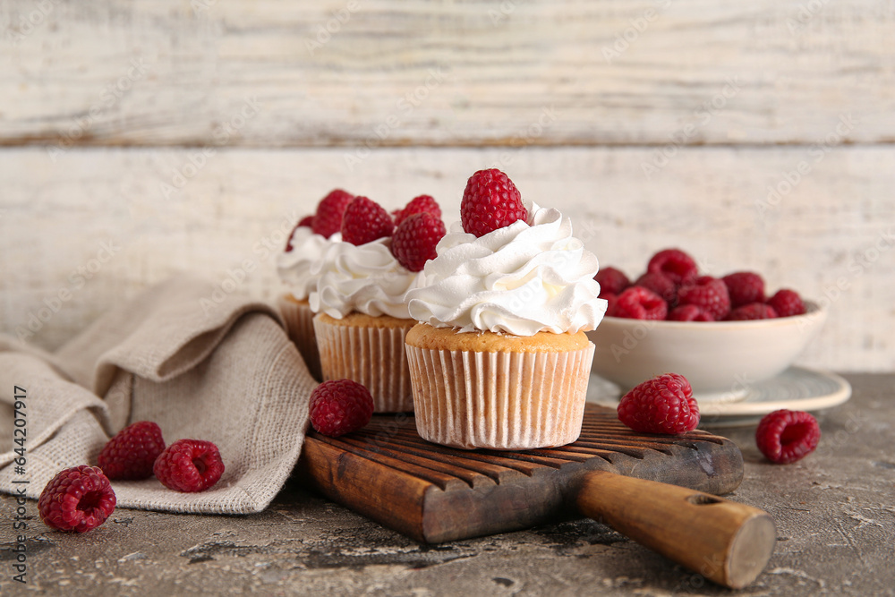 Wooden board of tasty raspberry cupcakes and fresh berries on table