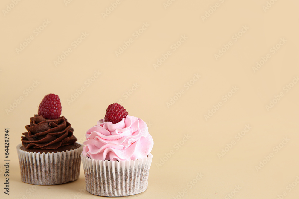 Tasty cupcakes with raspberries on beige background