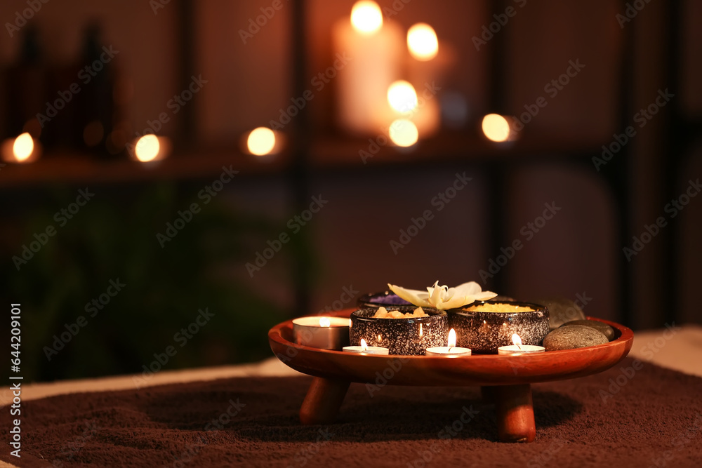 Spa composition with burning candles on table in dark salon, closeup