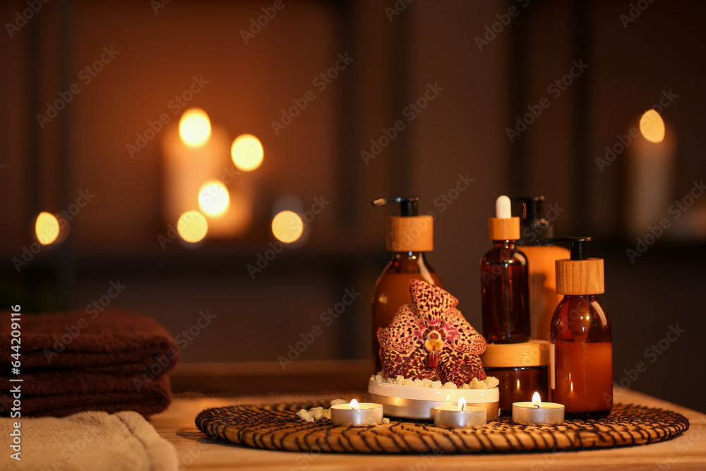 Spa composition with burning candles on table in dark salon, closeup