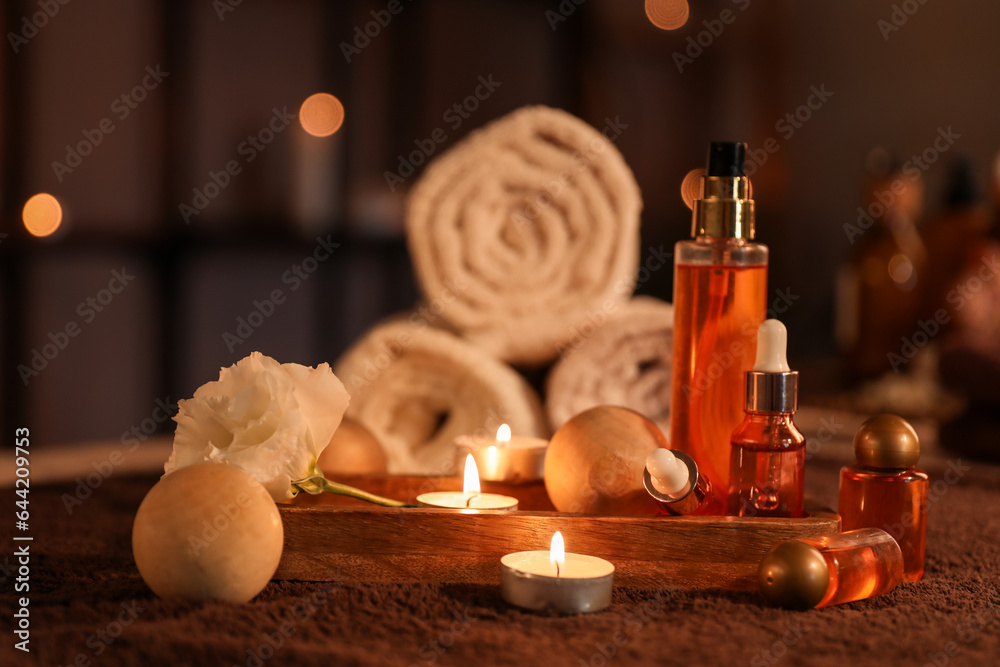 Spa composition with burning candles on table in dark salon, closeup