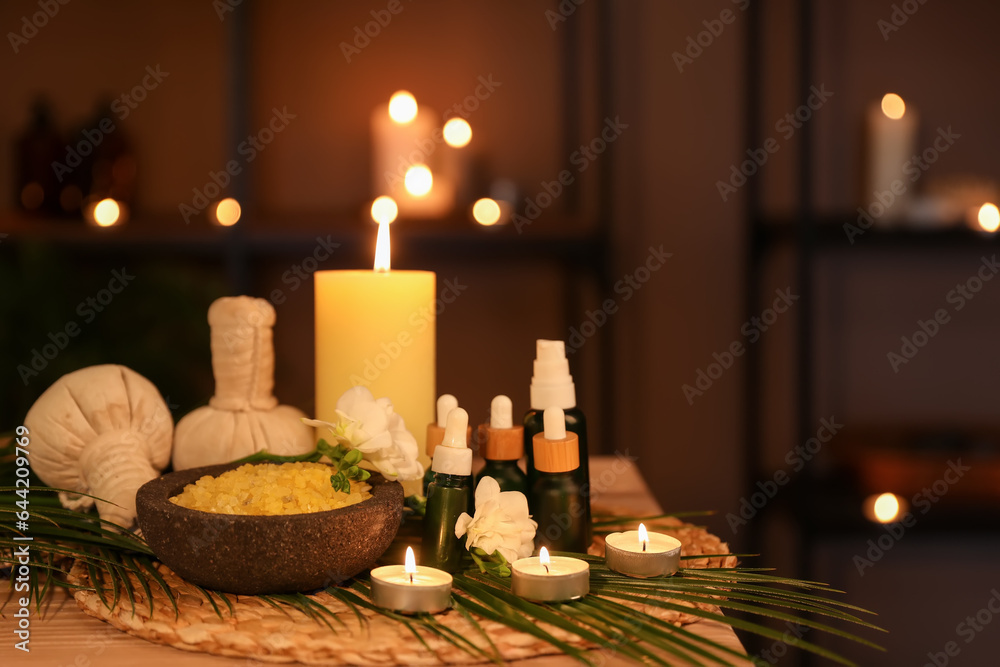 Spa composition with burning candles on table in dark salon, closeup