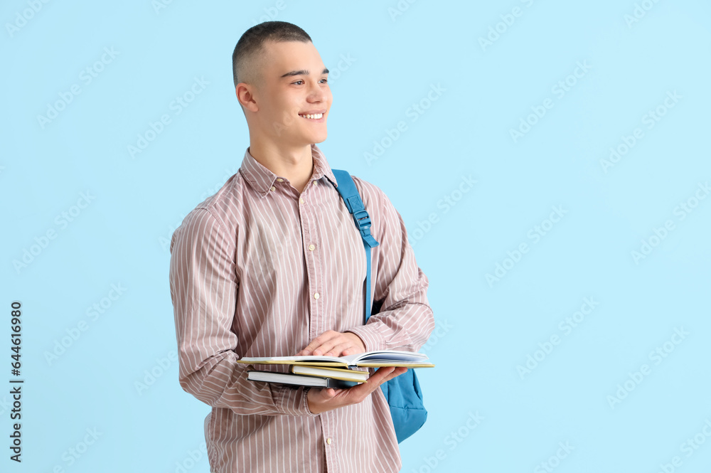 Male student with backpack and books on blue background