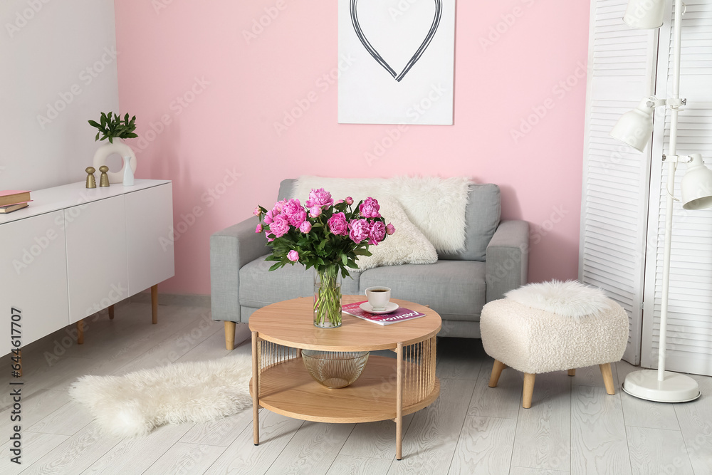 Vase of pink peonies on coffee table with couch in living room