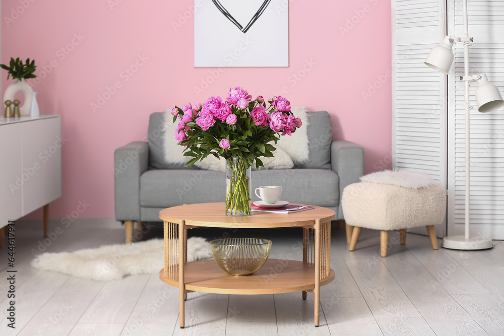 Vase of pink peonies on coffee table with couch in living room