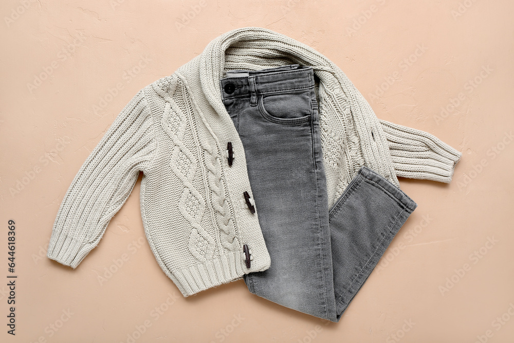 Knitted childrens sweater and jeans on color background