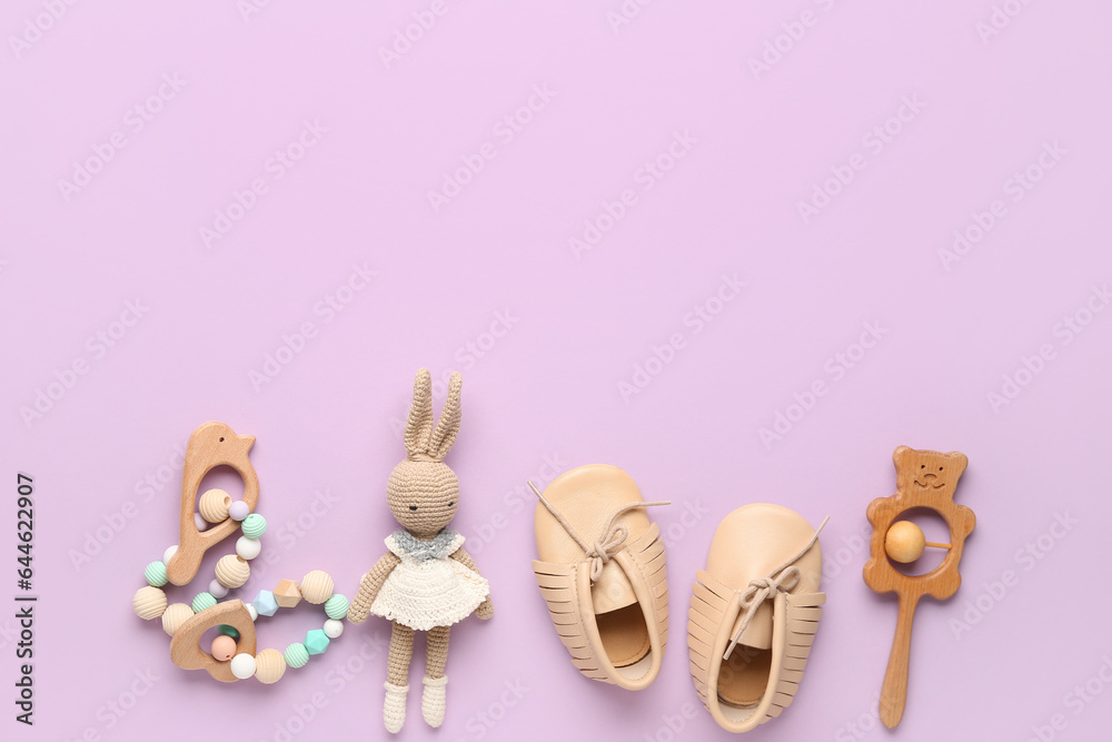 Baby booties and toys on pink background