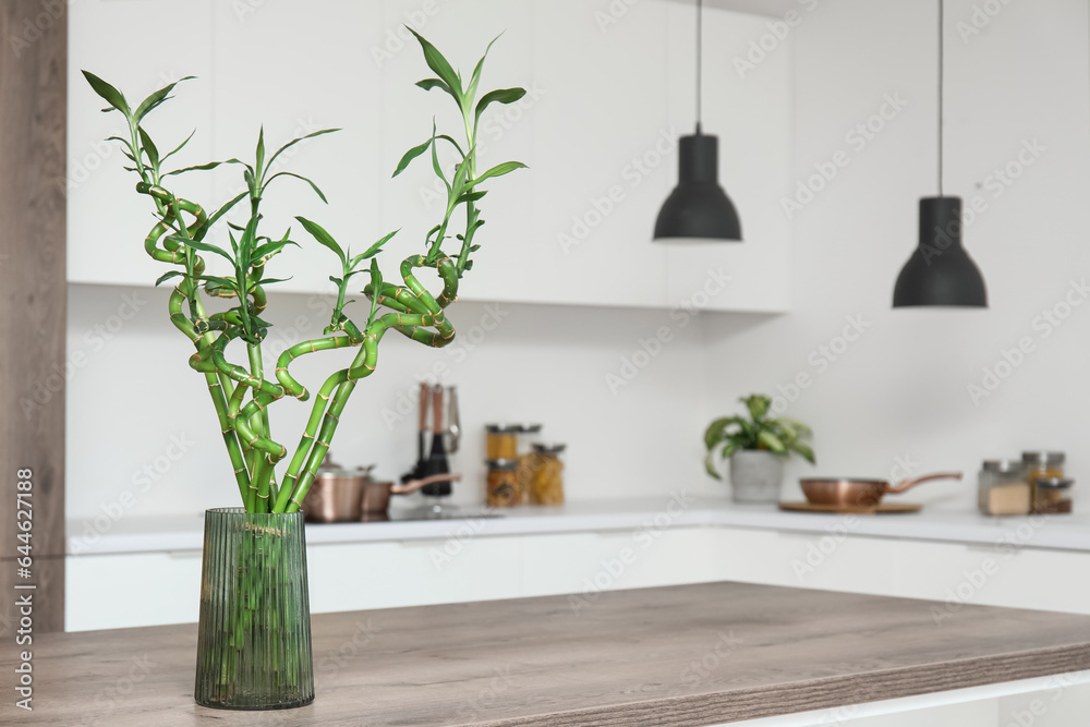 Vase with bamboo stems on table in kitchen