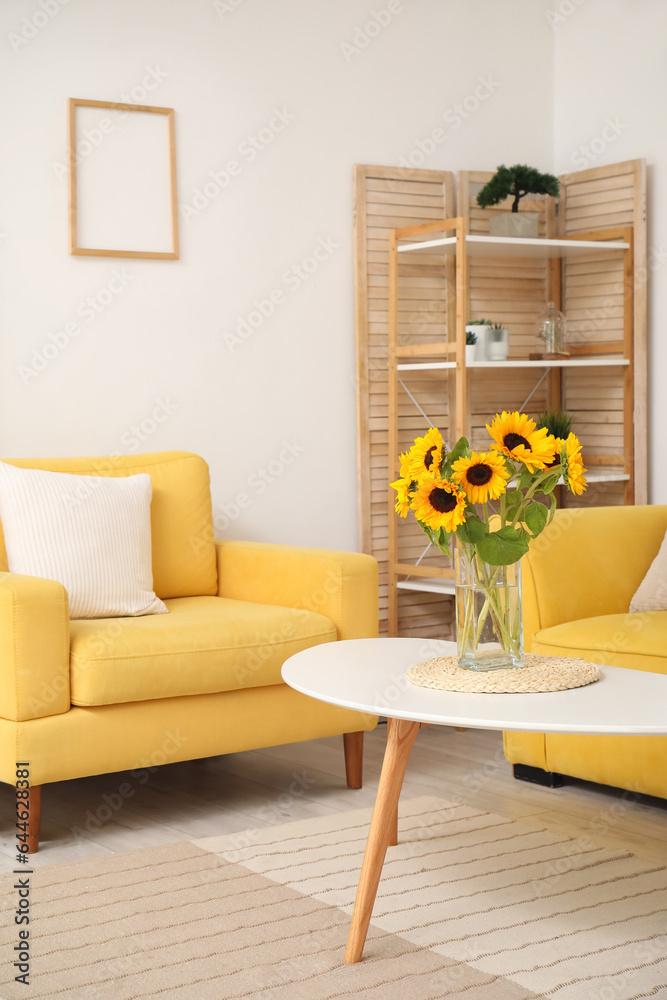 Vase with beautiful sunflowers and yellow armchair in interior of stylish living room