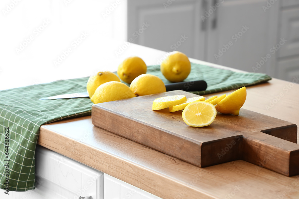 Wooden board with fresh lemons on wooden countertop in kitchen