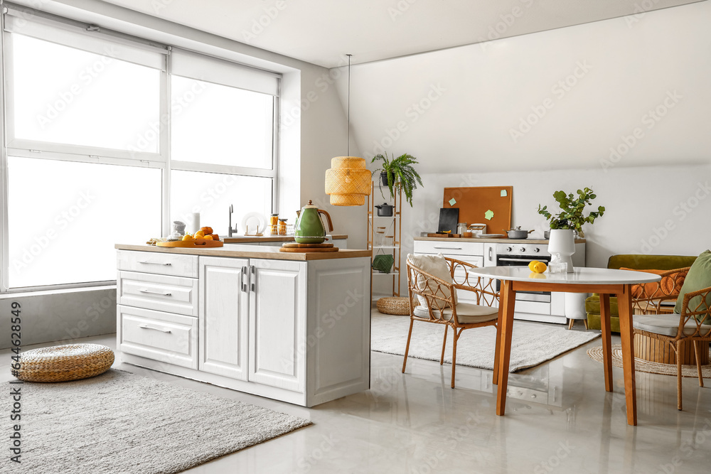 Interior of modern kitchen with white counters and dining table