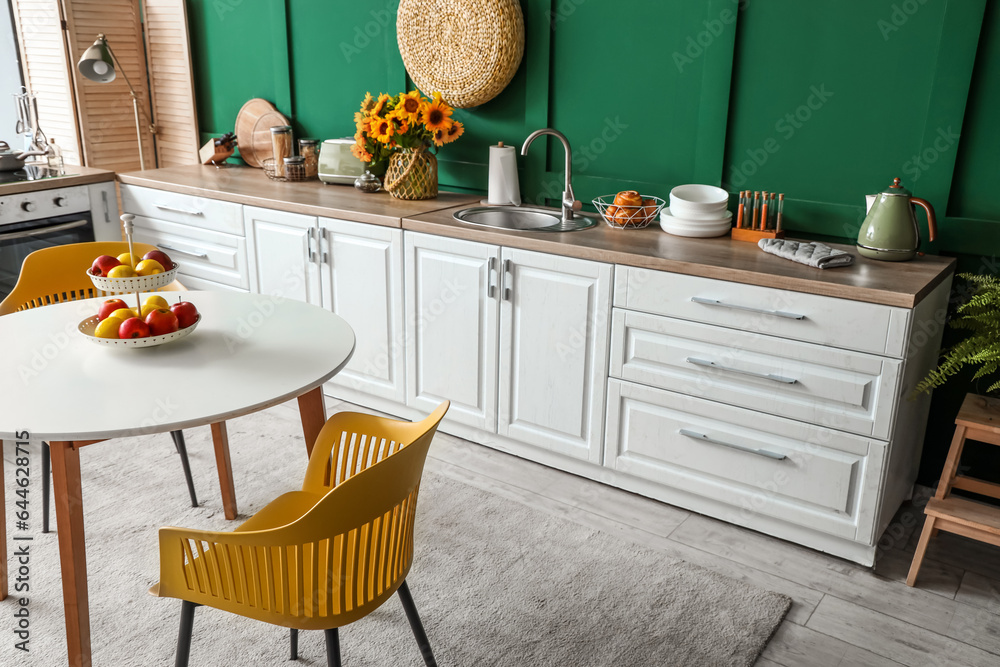 Interior of modern kitchen with white counters and dining table