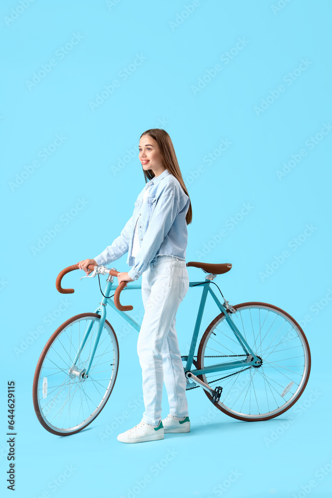 Young woman with bicycle on blue background