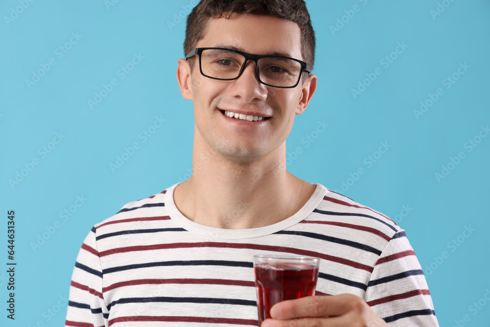 Young man with glass of juice on blue background, closeup