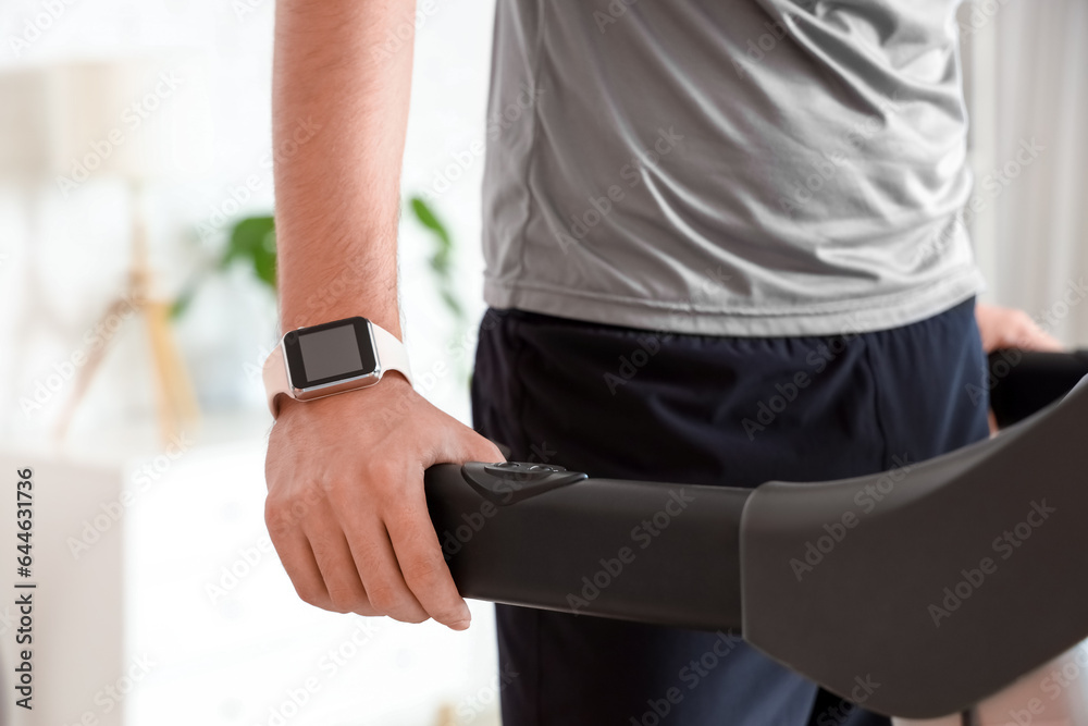 Sporty young man training on treadmill at home, closeup