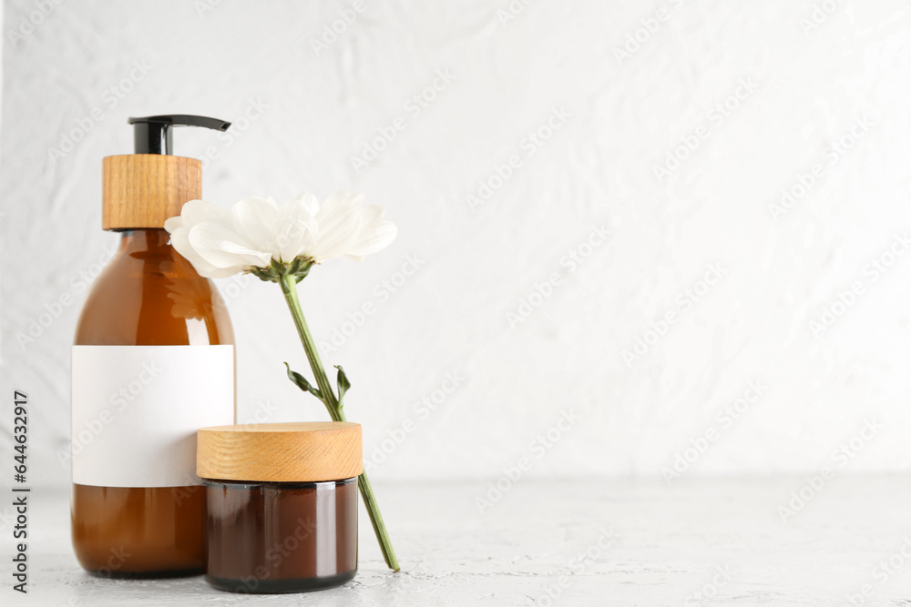 Cosmetic products and chamomile flower on light background