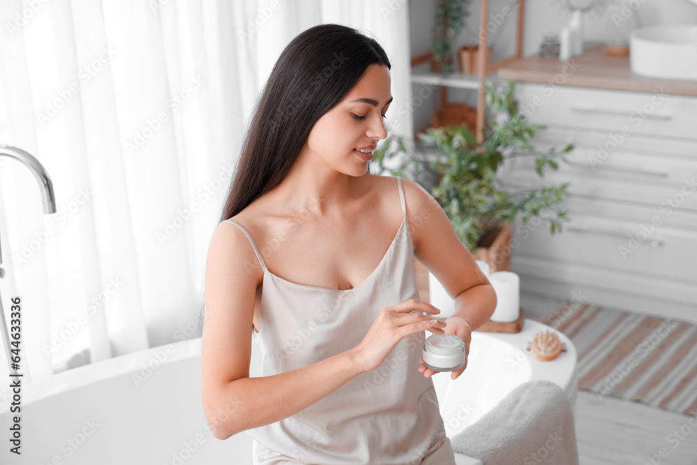 Young woman with jar of cream in bathroom