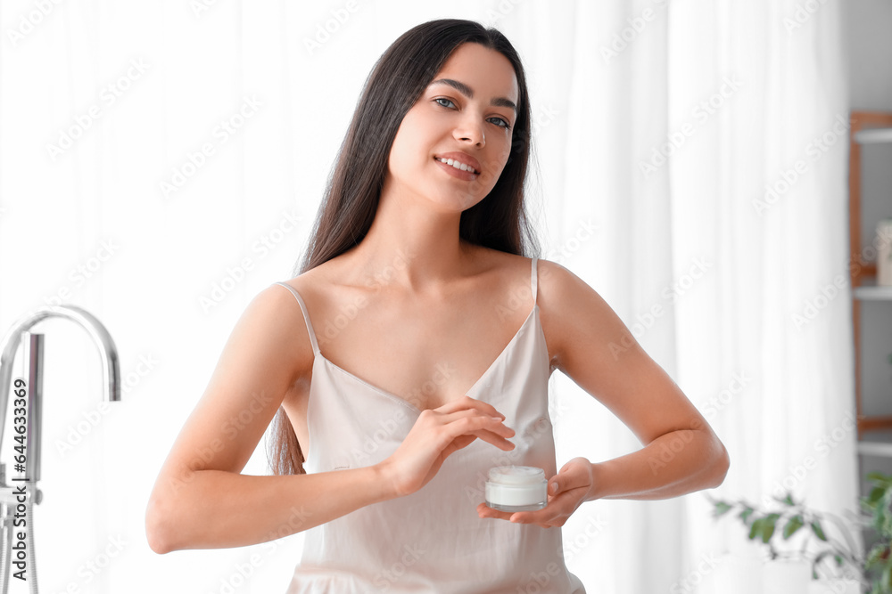 Young woman with jar of cream in bathroom