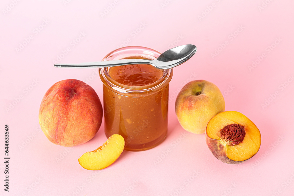 Jar with sweet peach jam and fresh fruits on pink background