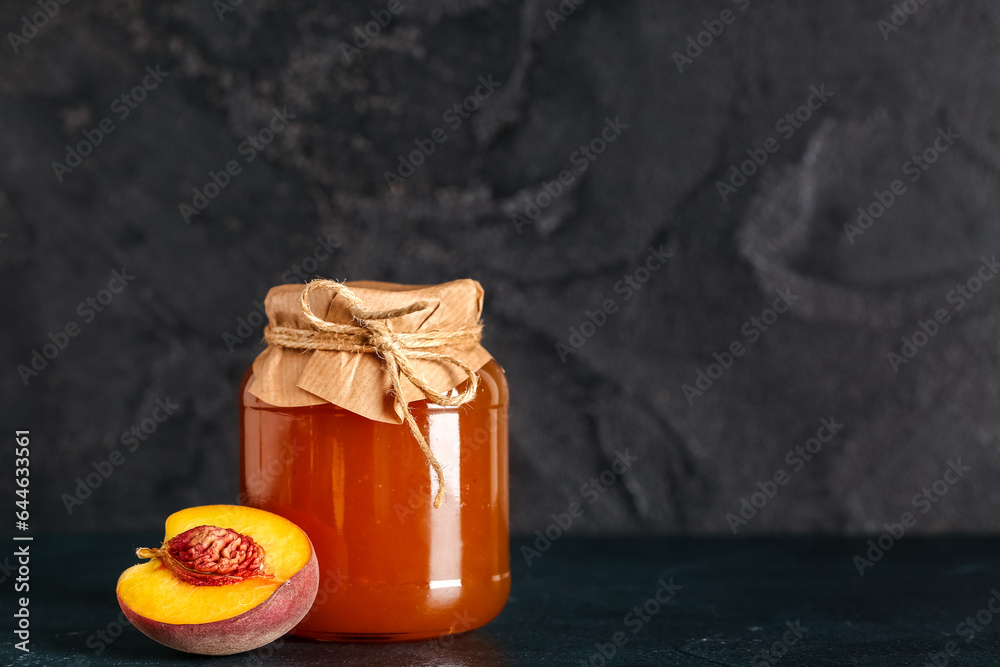 Jar with sweet peach jam on black background